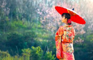 Einreise nach Japan: Neue Bestimmungen Einreise nach Japan: Junge Frau mit Kimono und rotem Papiersonnenschirm