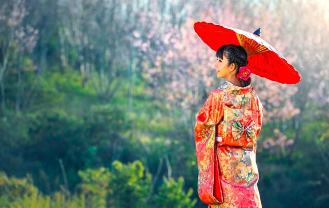 Einreise nach Japan: Junge Frau mit Kimono und rotem Papiersonnenschirm
