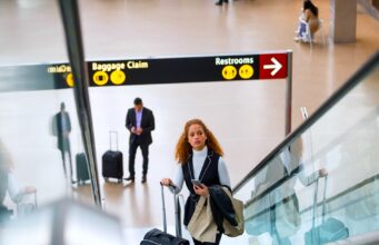 Kerosin-Debatte irritiert Geschäftsreisende Verwirrung rund um die Kerosin-Debatte: Frau mit Trollen auf einer Rolltreppe in einem Flughafen