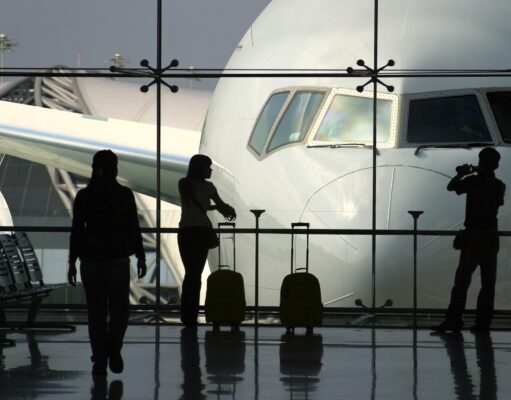 Geschäftsreisen: Die wichtigsten Key Insights Wie wichtig sind Geschäftsreisen wirklich? Eine Frau mit Handgepäck blickt von der Abflughalle durch einen großes Fenster auf ein Flugzeug