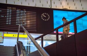 EU-Fluggastrechte stärken Passagierrechte EU.Fluggastrechte gesichert: Anzeigetafel auf einem Flughafen, eine Person steigt eine Treppe herab