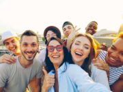 Kundenbindung im Tourismus neu gedacht Kundenbindung im Tourismus neu gedacht: Gruppe junger Männer und Frauen, die lachend den Fotografen anschauen und DAUMEN HOCHHEBEN