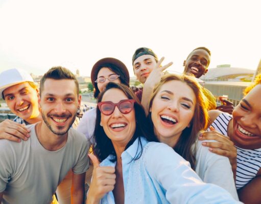 Kundenbindung im Tourismus neu gedacht Kundenbindung im Tourismus neu gedacht: Gruppe junger Männer und Frauen, die lachend den Fotografen anschauen und DAUMEN HOCHHEBEN