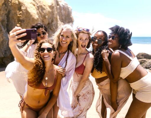 Social Media im Tourismus wird immer einflussreicher Social Media im Tourismus schlägt Wellen: Junge Gruppe von Frauen macht Selfies am Strand
