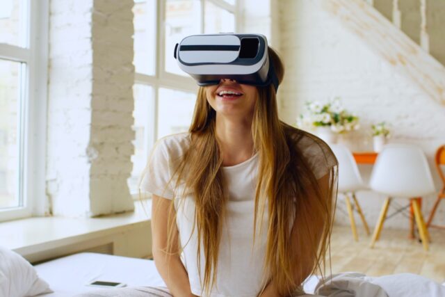 pexels-silverkblack-36812934 Innovationen im Tourismus: rau genießt eine virtuelle Realitätserfahrung zu Hause, lächelnd und entspannt.