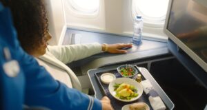 Das neue Bordservice: Grand Café KLM Bordservice Gand Café KLM: Frau sitzt im Flugzeug, vor ihr ein Tablett mit diversen Speisen