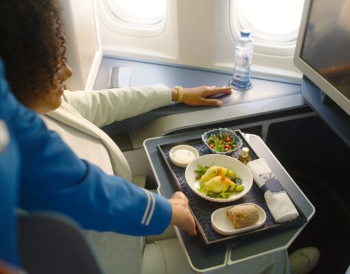 Das neue Bordservice: Grand Café KLM Bordservice Gand Café KLM: Frau sitzt im Flugzeug, vor ihr ein Tablett mit diversen Speisen