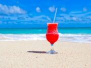 Karibik-Regionalnetz der Air France erweitert Karibik-Regionalnetz der Air France erweitert: Willkommen in Übersee. Auf weißem Sandstrand, im Hintergrund das blaue Meer und der blauen Himmel, steht ein Glas mit pinken Getränk und Strohhalm