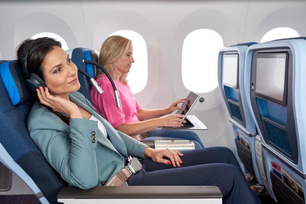Geschäftsreisen mit Air France und KLM: Zwei Frauen sitzen im Flugzeug, eine lauscht am Handy, die andere tippt etas auf ihren Laptop