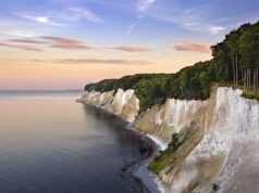 KI-Anwendung der DZT gewinnt Auszeichnung Eine Küstenlandschaft mit weißen Kreidefelsen entlang der Küstenlinie der Ostsee in Rügen und einem dichten Buchenwald im Nationalpark Jasmund darüber.