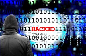 Warum Cyberangriffe auf Reisebüros zielen Cyberangriff auf Reisebüros: Ein Mann im Mantel und ein Monitor mit dem roten Titel „Hacker“ sowie verschiedene Daten im Hintergrund symbolisieren einen Cyberangrifdfd von einem Hacker