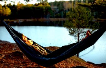 Wo „Introvertierte“ endlich urlauben können Urlaub für Introvertierte: A woman is lying in a hammock by a lake