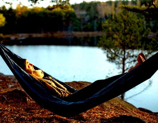 Wo „Introvertierte“ endlich urlauben können Urlaub für Introvertierte: A woman is lying in a hammock by a lake